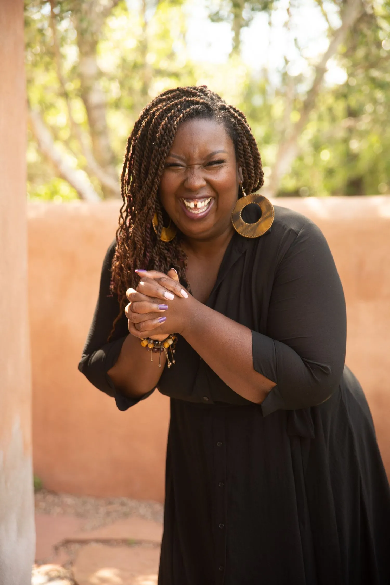Kali Shelton laughing in a black dress with braids, photographed outdoors